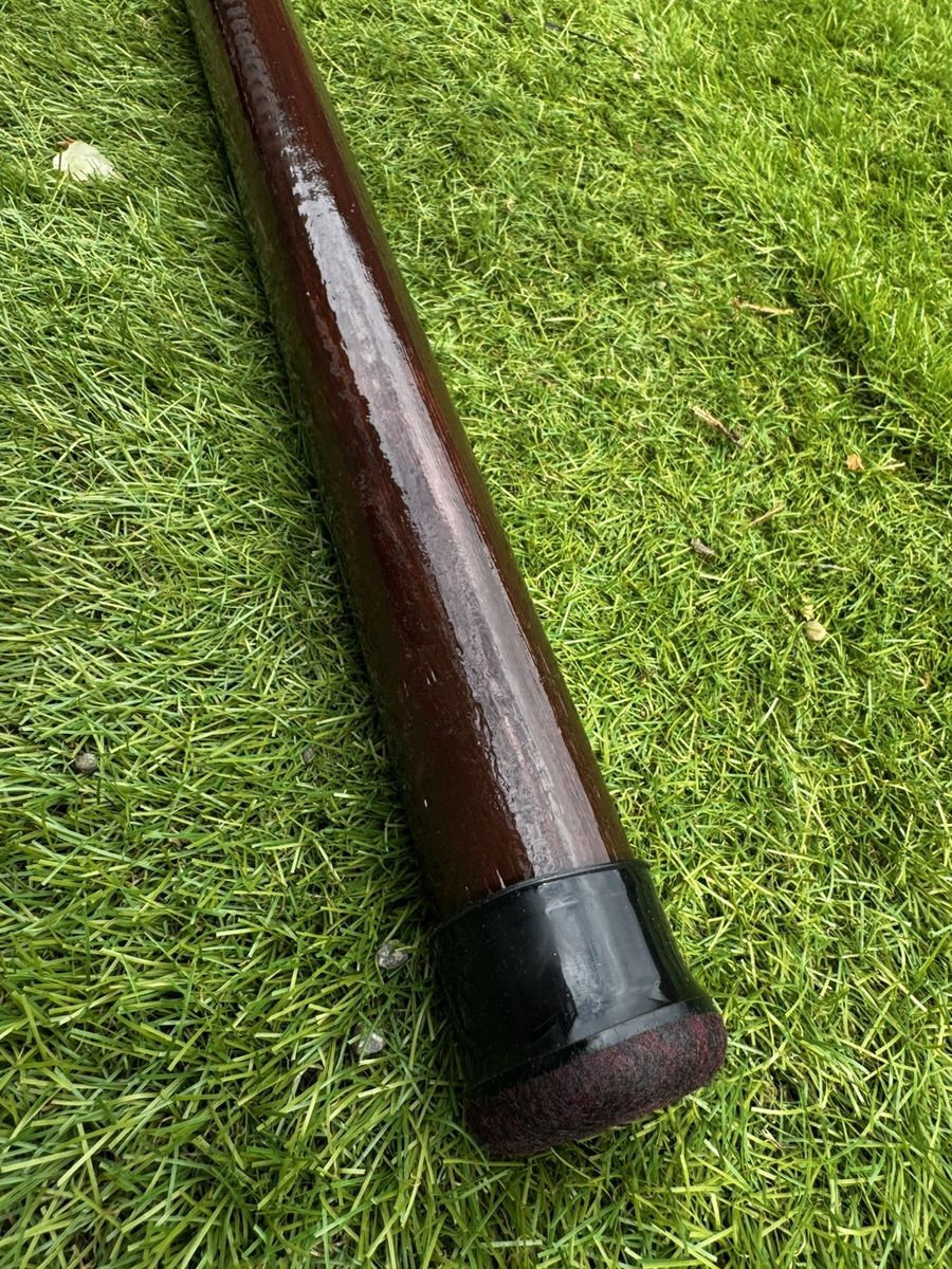 The hand-rounded end of a pole resting on grass